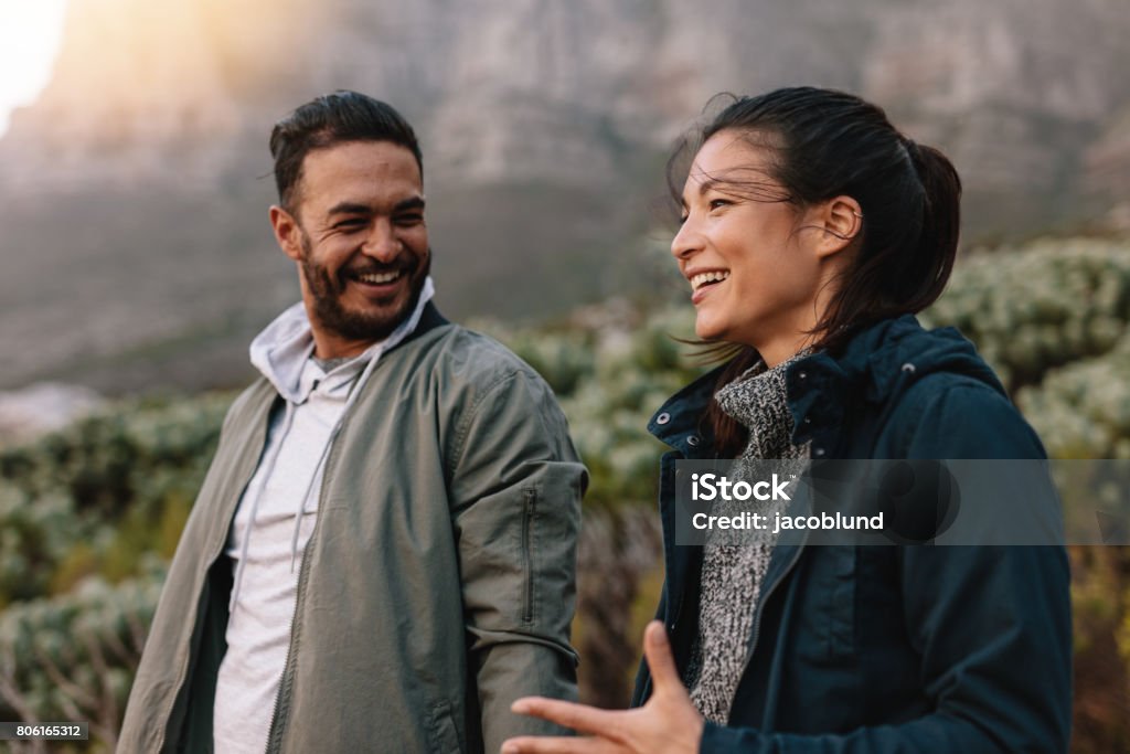 Happy couple walking and talking in the countryside Portrait of happy young couple walking and talking in the countryside. Young man and woman enjoying on a nature hike. Talking Stock Photo