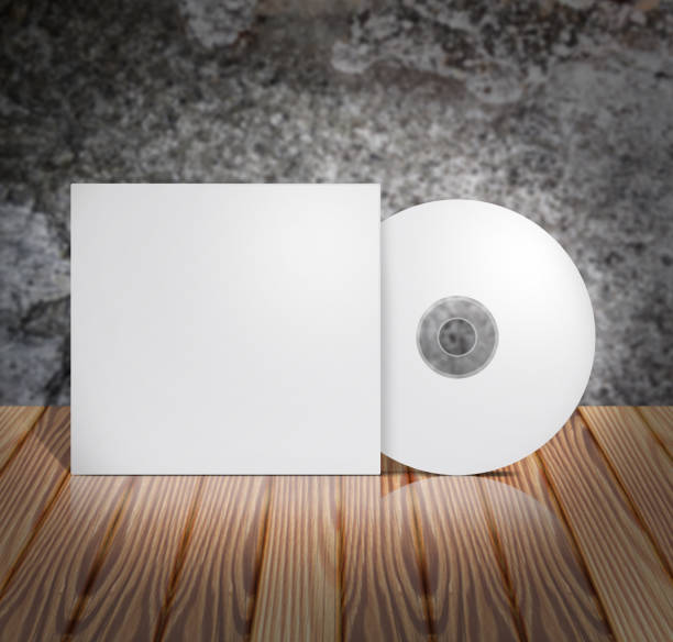 istock Blank white cd with cover on wooden table and concrete wall background. Mock up, 3D illustration. 806197098