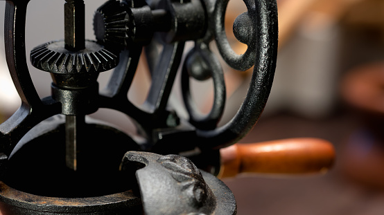 Hand old-fashioned coffee grinder top fragment with rotating mechanism. Close-up