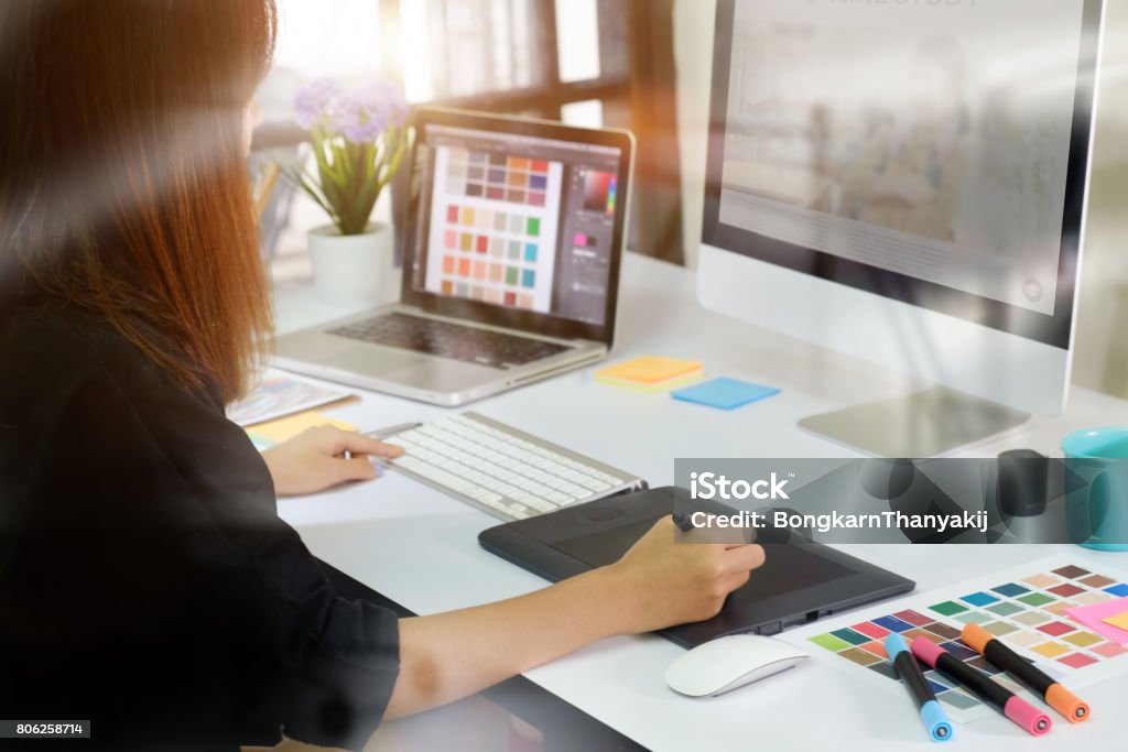 Young asian graphic designer working on computer. Young asian graphic designer working on computer using digital tablet at office. Adult Stock Photo