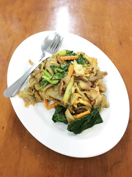 weiß auf holztisch flachen gebratene nudeln und schweinefleisch mit erhaltenen soja-bohnen-paste einrühren. thailändische küche. - tofu chinese cuisine vegetarian food broccoli stock-fotos und bilder