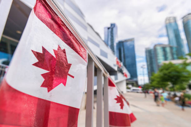 canada plastic flag with blurred urban background in toronto - canadian flag canada flag canada day imagens e fotografias de stock