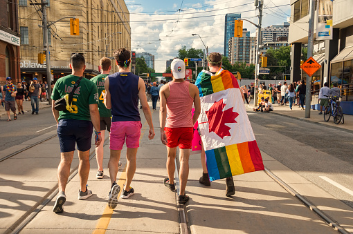 Toronto, Canada - 25 June 2017: Rear view of a group of five young men walking on Church Street after Pride Parade.