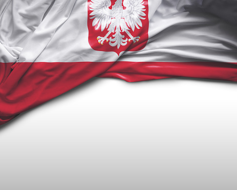 A closeup of the red and white flag of Poland flying in a stiff wind.  This flag is a variant of the usual red and white Polish flag with the national coat of arms in the middle of the white stripe.  It is normally reserved for official use abroad and at sea.