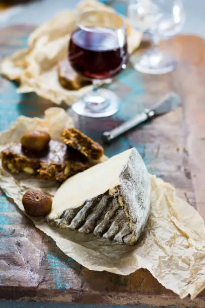 Sweet dessert liqueur wine in glass, hard French cheese Tomme de Montagne and dried figs with figs bread, still life
