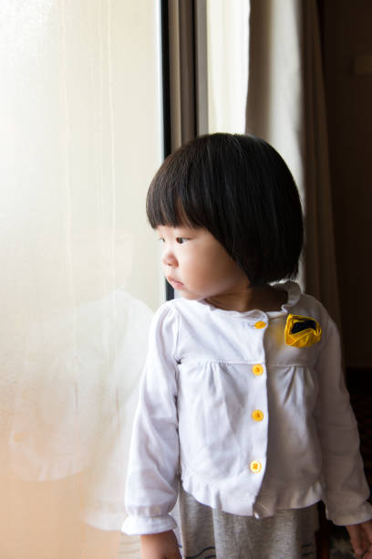 istock Asian toddler watching the rain through window 806321072