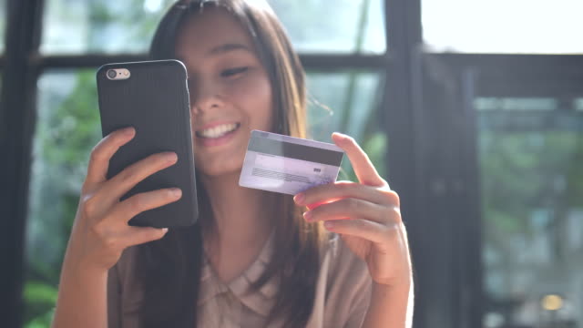 Young Asian woman shopping on mobile phone with Credit card