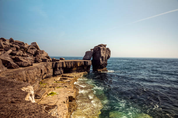 Seascape depicting the Pulpit Rock from the Quarries pathway, surrounded by blue skies and calm seas on a beautiful summers day. Portland, Dorset, Unites Kingdom.