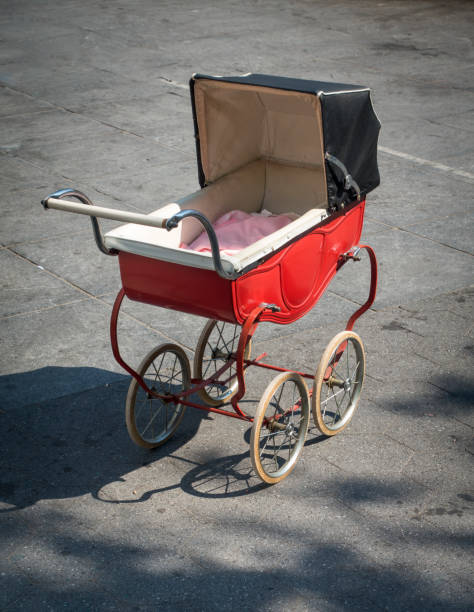 A red and black unattended baby carriage on a sidewalk in New York City