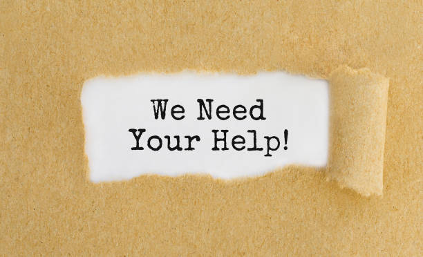 Text We Need Your Help appearing behind ripped brown paper stock photo