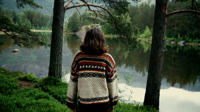 Young Caucasian woman standing near the lake in forest in Norway