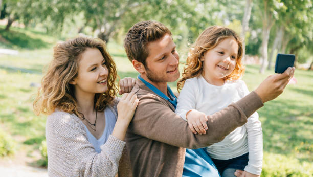 istock Cheerful young family taking selfie at park 806372520