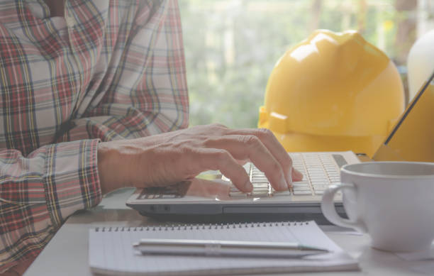 istock Architect engineer using laptop for working with yellow helmet, laptop and coffee cup on table. 806381166