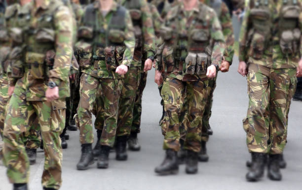 scena del personale militare che marcia per strada - paramilitary foto e immagini stock