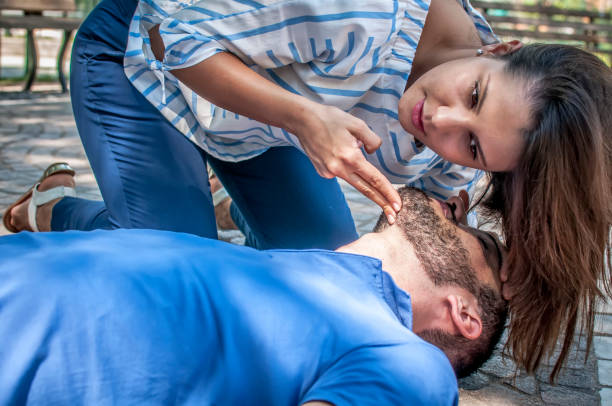 istock girl assists unconscious young man and controls breathing and vital parameters 806405476