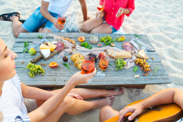 istock Young friends drinking rose wine on summer beach picnic 806436346