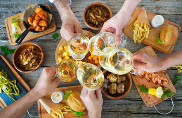 istock People with white wine toasting over served table with food. 806438644