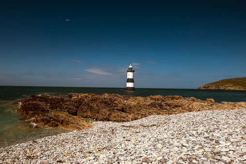 Beautiful seascape depicting Penmon Lighthouse and surrounding coastal features, (Trwyn Du, Perch Rock, Ynys Seiriol, Puffin Island)  on a summers day with clear blue skies and calm seas.