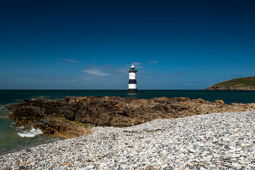 Beautiful seascape depicting Penmon Lighthouse and surrounding coastal features, (Trwyn Du, Perch Rock, Ynys Seiriol, Puffin Island)  on a summers day with clear blue skies and calm seas.
