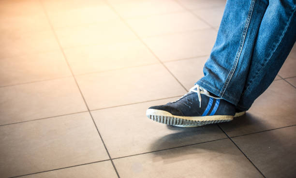 istock legs of a man in sneakers on a tiled floor. 806465952