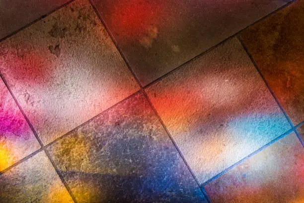 Colorful reflections of stained glass murals on stone ground closeup