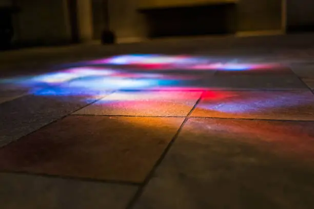 Colorful reflections of stained glass murals on stone ground closeup