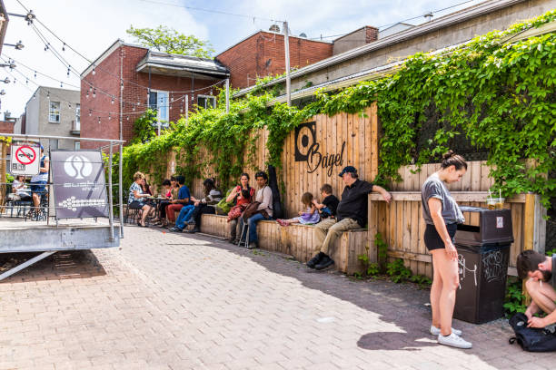 people sitting outside restaurants near jean-talon farmers with bagel and sushi signs during bright sunny day at - 2042 imagens e fotografias de stock