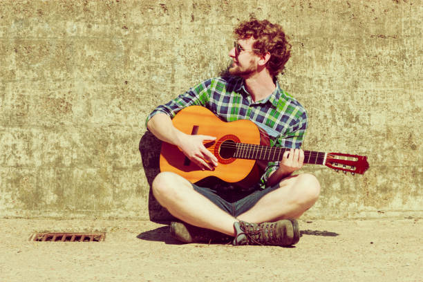 istock Young bearded hipster man with guitar outdoor 806502024