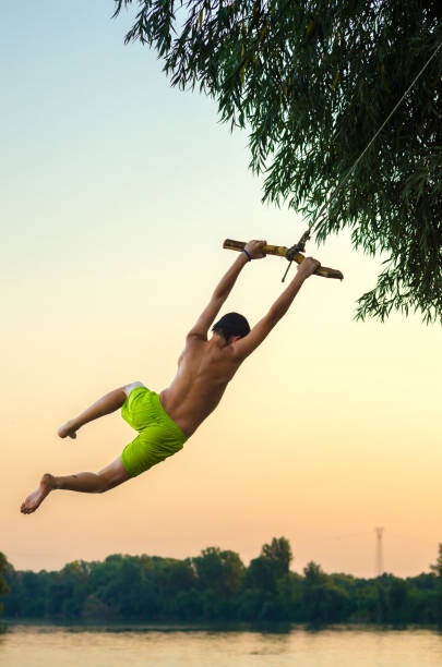 istock Boy jumping into the river from the swinging rope 806545640