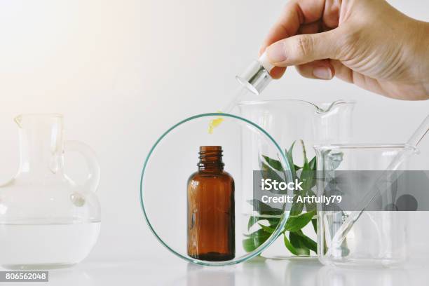 Foto de Recipientes De Cosméticos Garrafa Marrom E Vidraria Científica Foco Em Óleo Caindo Em Pacote De Rótulo Em Branco Para A Marca Mockup e mais fotos de stock de Laboratório