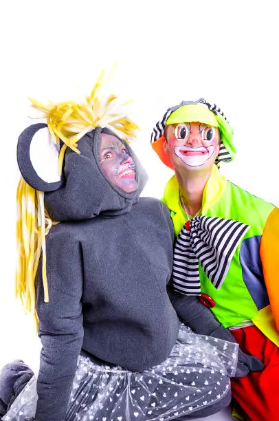 Portrait of two smiling and fooling around animators in theater role - grey mouse and clown. Emotional and colorful. Isolated background