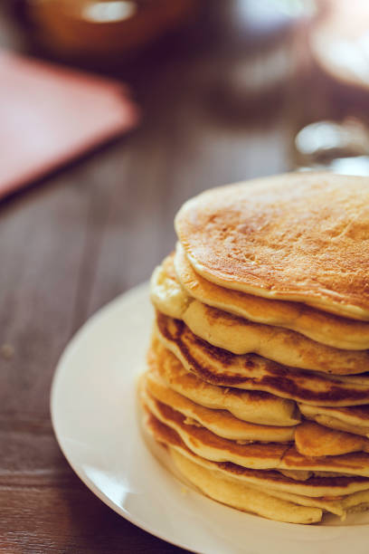 Two pancakes with butter on a plate on a wooden table.