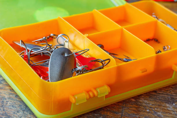 iscas de pesca de metal em um closeup de caixa de armazenamento de plástico laranja - fishing fishing hook metal animal imitation - fotografias e filmes do acervo