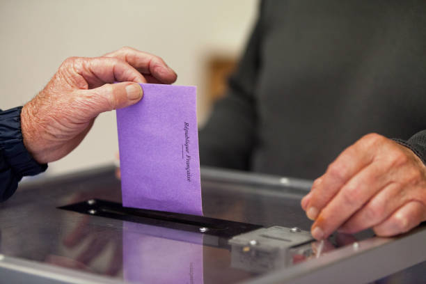 Ballot Box - Election - France A senior inserting his vote through the slot of the ballot box during the election. voting ballot box voting ballot polling place stock pictures, royalty-free photos & images