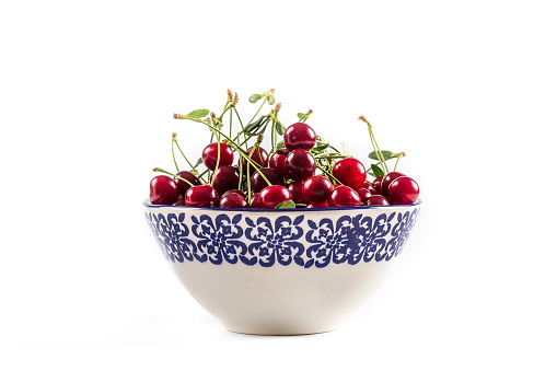 red cherry in wooden bowl isolated on white background. clipping path. top view