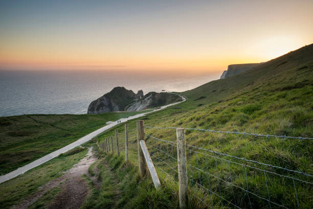 istock Vibrant sunset over sea stack on English coast during Spring with tourists on footpath 806765482
