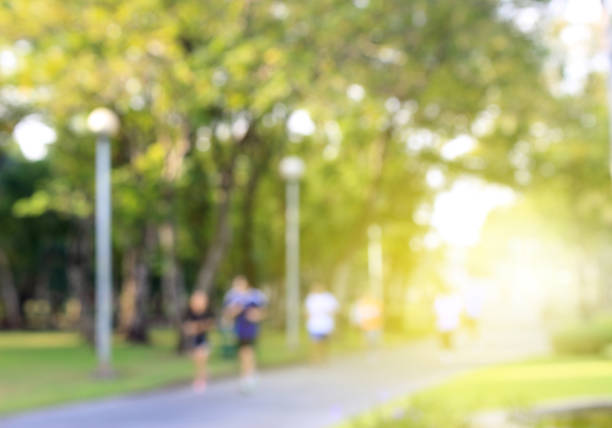 Blurred background of people running in park with burst light