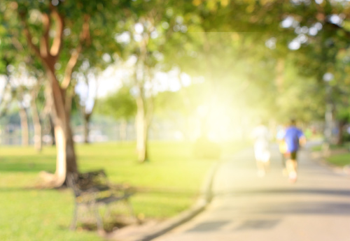 Blurred background of people running in park with burst light
