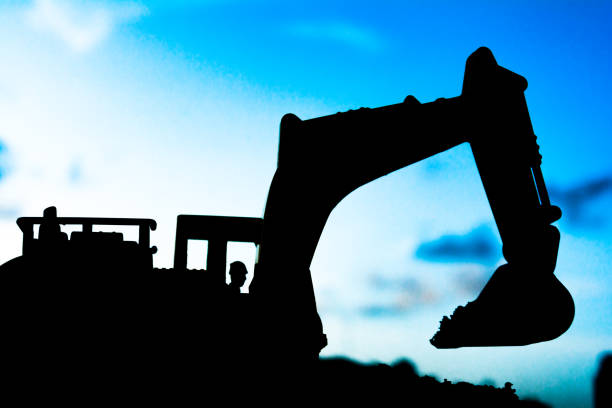 istock silhouette tracked excavator Sand and stone And sky background 806808236