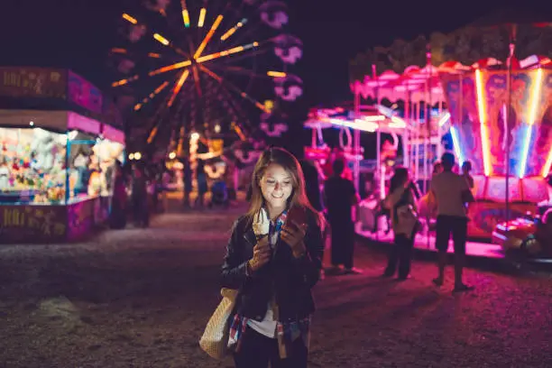 Photo of Young woman at the funfair text messaging