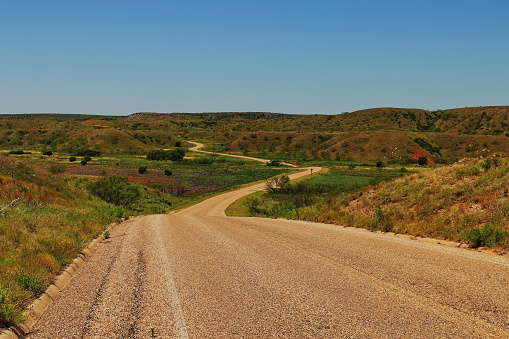 A two lane blacktop road winds its way through the Texas Panhandle near the Oklahoma border