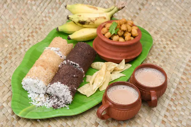 Popular South Indian breakfast puttu / pittu made of white rice flour and coconut in a bamboo mould, with banana, Kerala, India. Bamboo puttu prepared in the bamboo utensil.