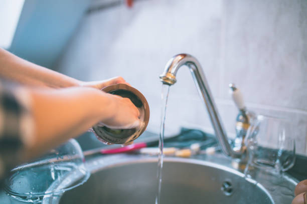 istock Beautiful smiling young woman washing a cup in white kitchen. 806876378