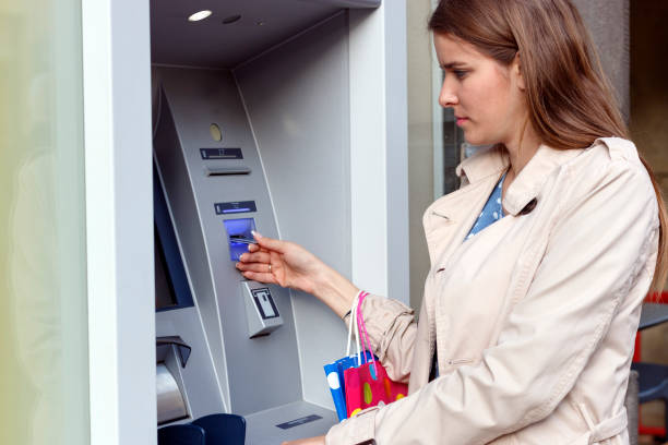 istock Beautiful girl inserting a credit card to ATM machine 806909570
