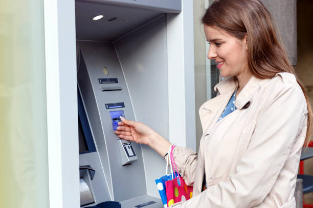 istock Beautiful girl inserting a credit card to ATM machine 806909596