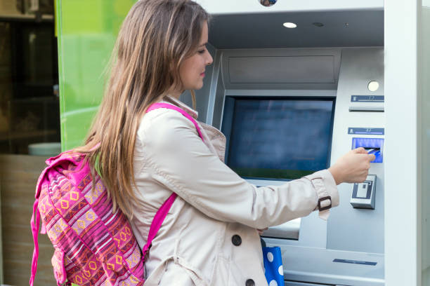 istock Beautiful girl inserting a credit card to ATM machine 806911736