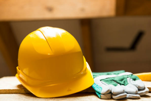 istock Yellow safety helmet and gloves on working surface at attic renovation site 806911802
