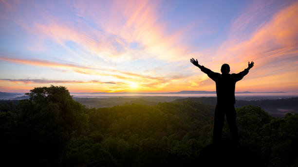 silueta de hombre levantó las manos con las montañas del paisaje al atardecer - adorando a dios fotografías e imágenes de stock