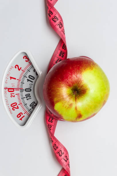 istock Apple with measuring tape on weight scale. Dieting 806949940