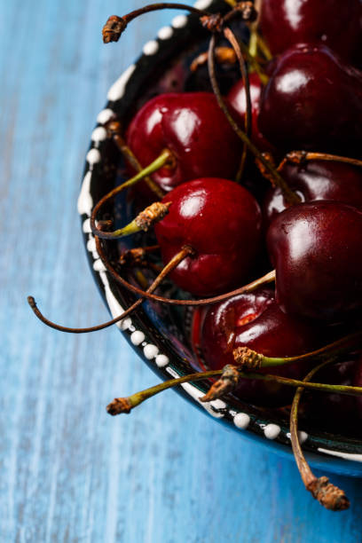 Cherry in a blue bowl close-up on a blue Cherry in a blue bowl close-up on a blue background Cirrocumulus stock pictures, royalty-free photos & images